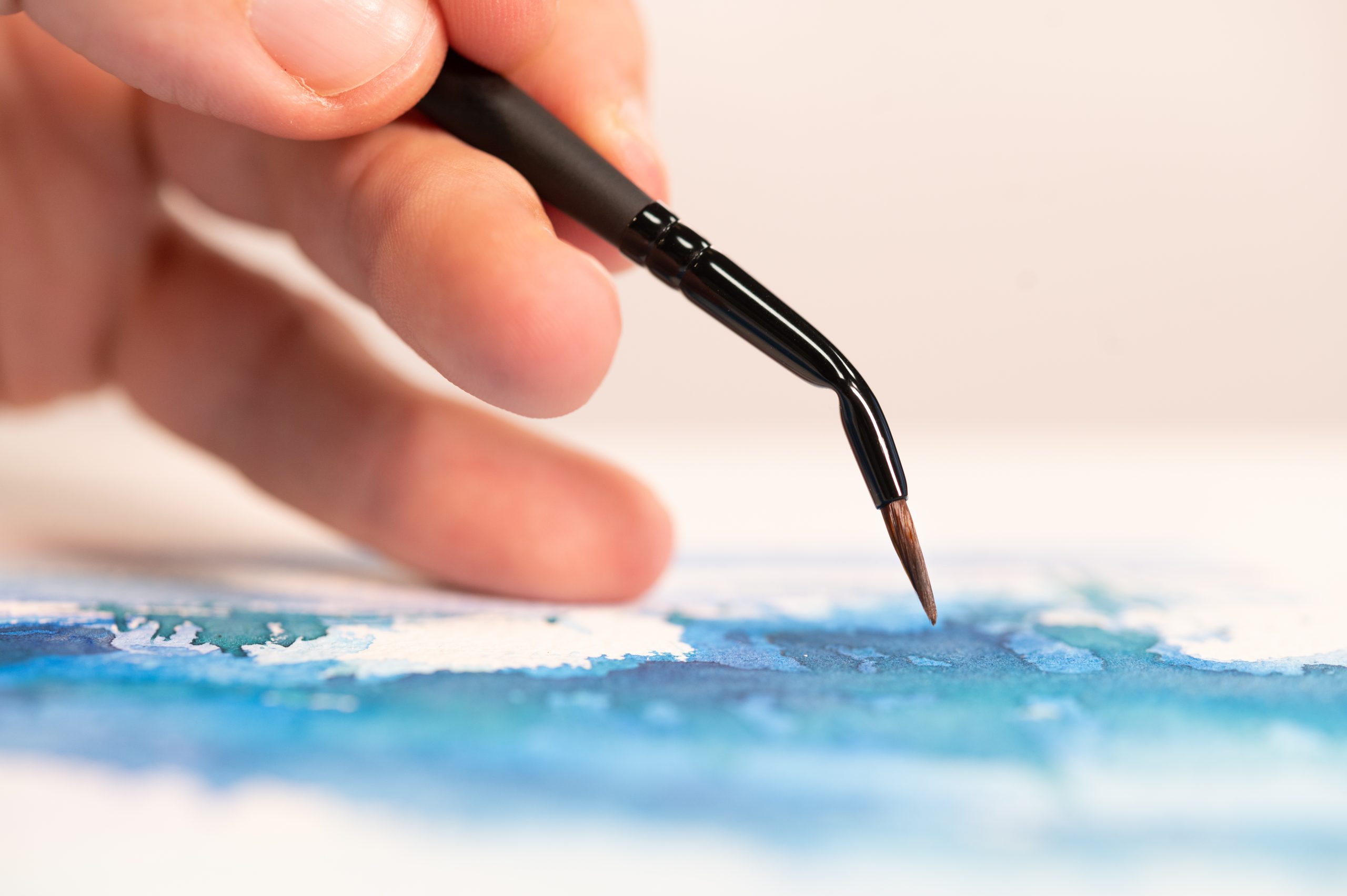 Trois pinceaux Stradivarius posés sur une aquarelle de paysage