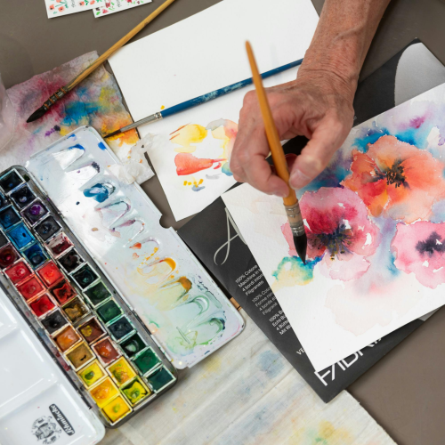 main qui peint des fleurs à l'aquarelle